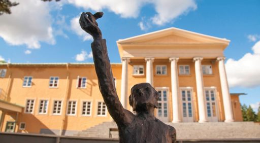 En av statyerna framför Midgården i solljus