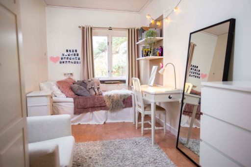 Ett mysigt sovrum på Berga, med spegel, byrå, skrivbord och säng.